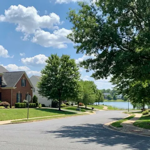 Suburban neighborhood street in Bristow, Virginia with colonial-style brick homes and mature trees