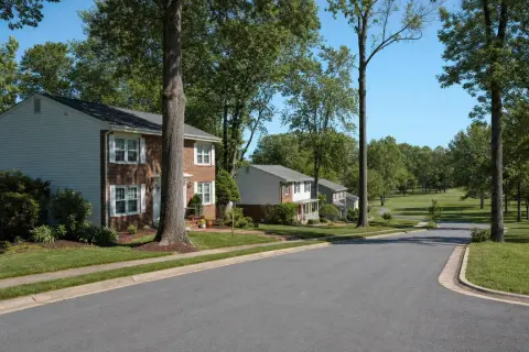 Curving residential street in Crofton Maryland with brick-front colonial homes, mature trees, and a golf course fairway