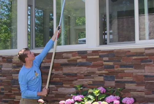 Better Termite technician removing spider webs from home exterior in Springfield, Virginia