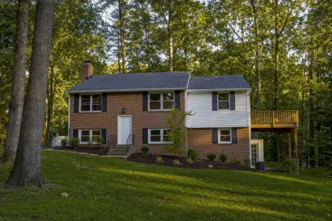 Brick and siding split-foyer home with a rear deck on a sloped, wooded lot in Ellicott City, Maryland