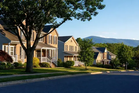 Brick-front colonial homes with white porches on a tree-lined Frederick, Maryland street with Catoctin Mountain in the distance