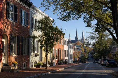 Street of historic brick rowhouses in downtown Frederick, Maryland with church spires visible beyond the rooftops