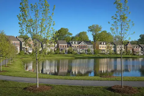 Row of colorful townhomes across a small lake with a walking path in a Gaithersburg Maryland neighborhood