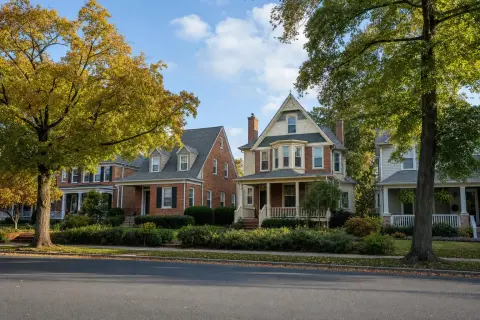Tree-lined residential street in Gaithersburg Maryland with brick townhomes and Victorian-style single family houses