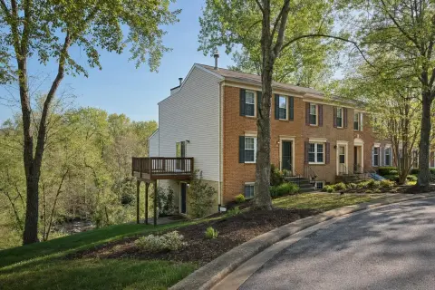 Brick and vinyl end-unit townhome in Germantown Maryland with a wood deck over a walk-out basement backing to a wooded stream valley