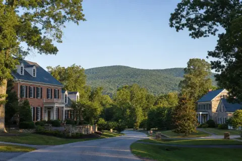 Residential street of brick and stone-front homes in Haymarket, Virginia with the wooded ridge of the Bull Run Mountains behind