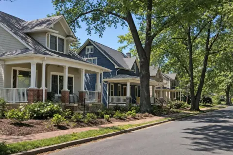 Porch-front bungalows and foursquare homes under mature shade trees on a brick-sidewalk street in the Hyattsville Historic District, Maryland