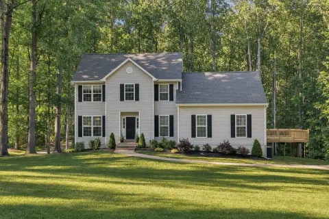 Two-story vinyl-sided home with mulch beds and a back deck on a wooded one-acre lot in La Plata, Maryland