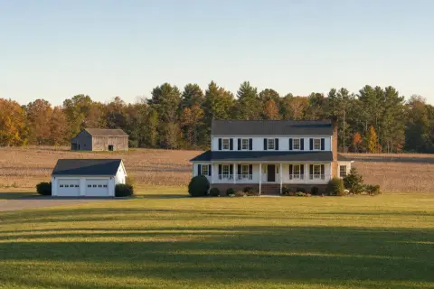 Two-story colonial home on a large lawn at the edge of La Plata, Maryland, with a harvested field, an old tobacco barn, and a tree line behind it