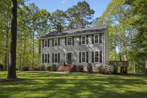 Two-story colonial home with a brick front stoop, wooden deck, and mulch beds on a wooded lot in La Plata, Maryland