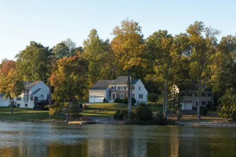 Two-story colonial homes on wooded lots above a calm lake in Montclair, Virginia in early autumn