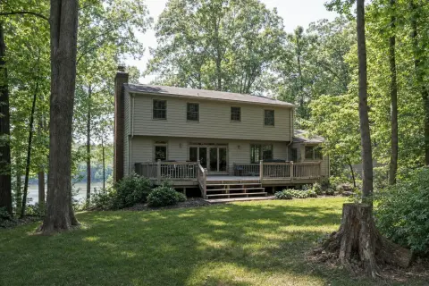 Two-story 1980s colonial with a wood deck on a wooded lot above a lake in Montclair, Virginia