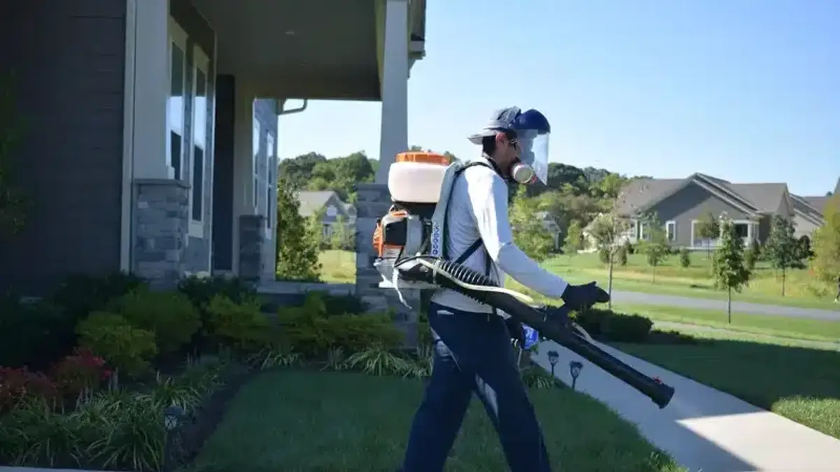 Technician applying a mosquito treatment to shrubs in a residential yard