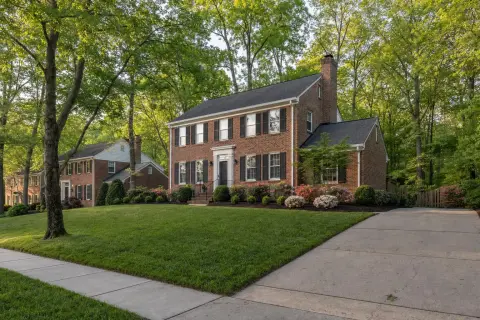 Brick colonial homes with fresh mulch beds and azaleas on a tree-lined Northern Virginia street in late spring