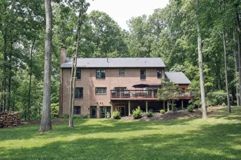 Brick colonial in Oakton, Virginia with a walkout basement and an elevated wood deck on a sloped, wooded lot