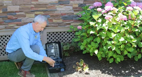 Better Termite technician servicing rodent bait station at residential property near Great Falls Virginia