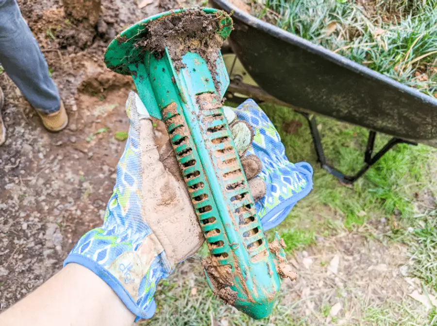 Technician inspecting outdoor bait stations at a home foundation