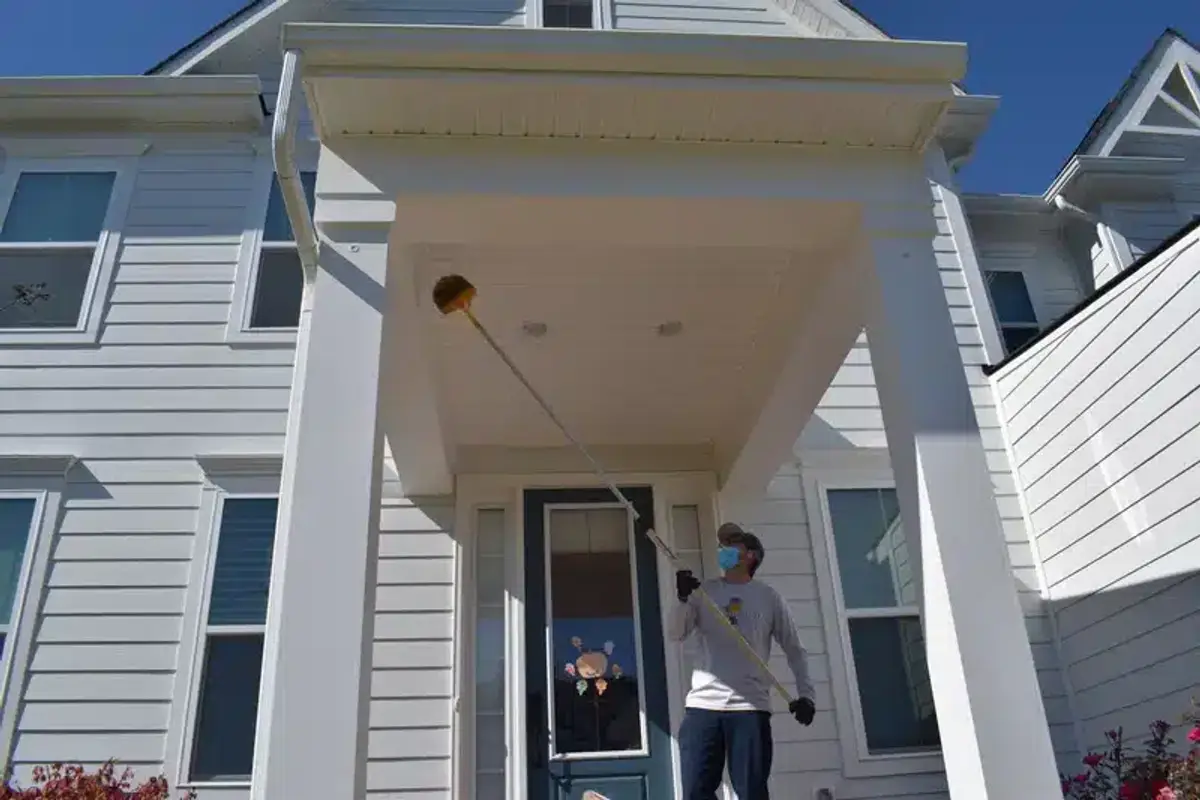 Professional pest control technician performing exclusion work on home exterior