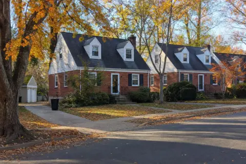 Row of 1940s red-brick Cape Cod homes with dormers on a leafy autumn street in Silver Spring, Maryland