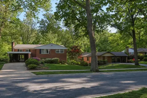 Mid-century brick split-level and rambler homes under tall oak trees on a Silver Spring, Maryland street