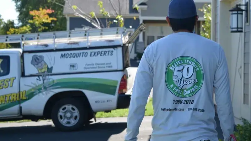 Licensed pest control technician with company truck featuring 57 years of service badge